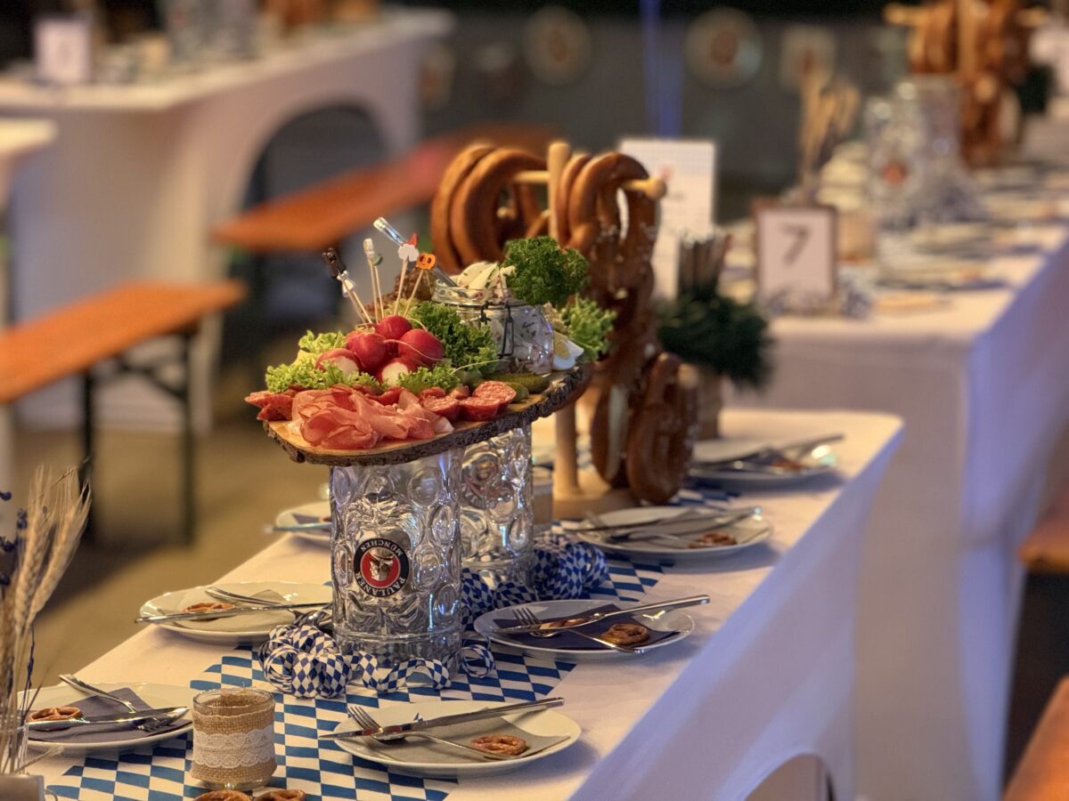 Historisches Gewölbe im Oktoberfest-Stil mit Birkenbäumen, Biertischen und festlicher Beleuchtung